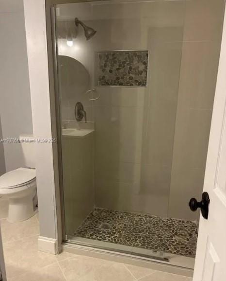 bathroom with tile patterned flooring, an enclosed shower, and toilet