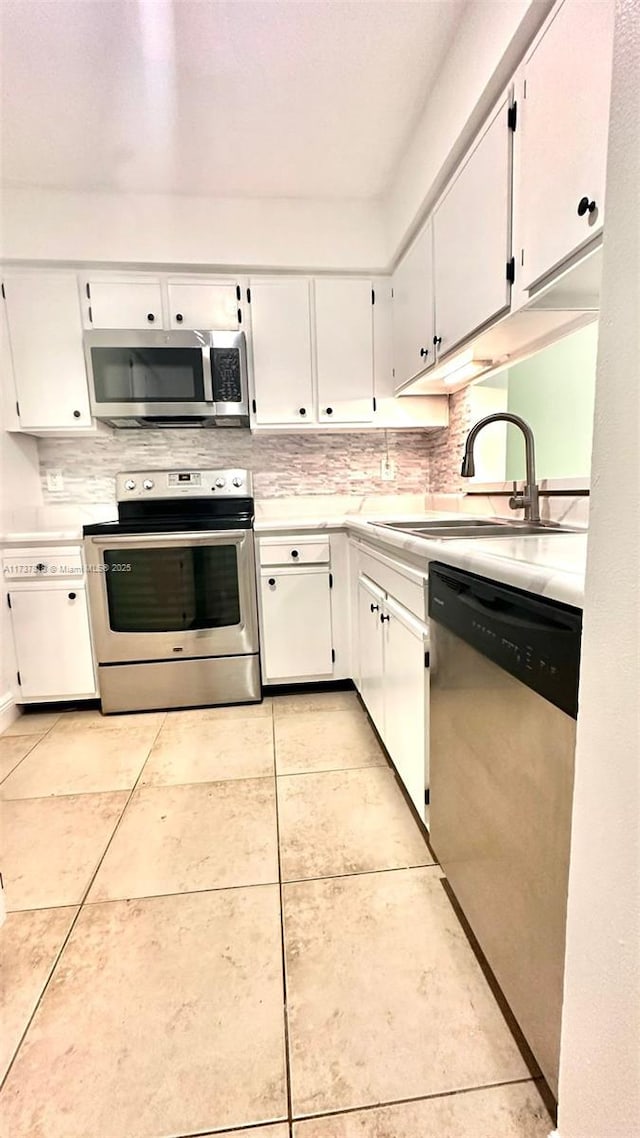 kitchen featuring sink, decorative backsplash, stainless steel appliances, and white cabinets