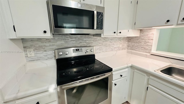 kitchen featuring appliances with stainless steel finishes, white cabinets, and backsplash