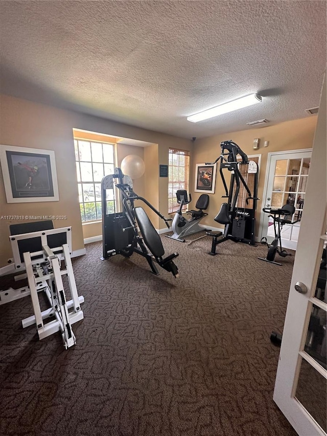 workout area with dark carpet and a textured ceiling