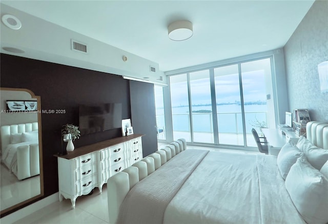 bedroom featuring access to outside, a wall of windows, and a water view