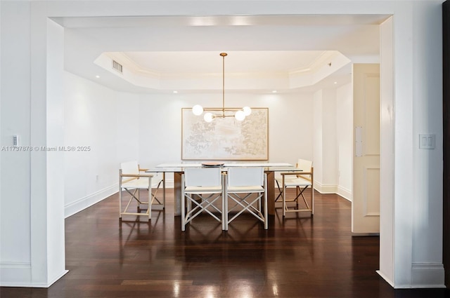 dining space with visible vents, baseboards, a tray ceiling, and wood finished floors