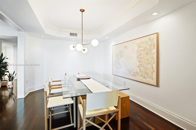 dining space with visible vents, a raised ceiling, ornamental molding, dark wood-style floors, and baseboards