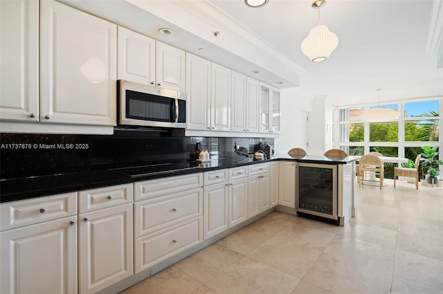 kitchen featuring tasteful backsplash, stainless steel microwave, black electric stovetop, beverage cooler, and white cabinets