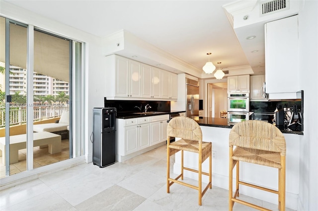 kitchen with visible vents, a sink, dark countertops, backsplash, and appliances with stainless steel finishes