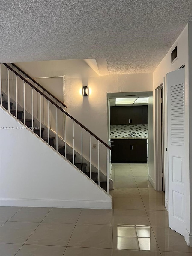 stairway with tile patterned flooring and a textured ceiling