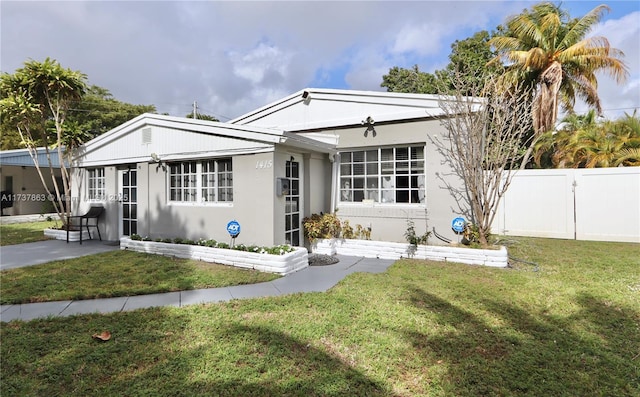 view of front of house featuring a front yard, fence, and stucco siding