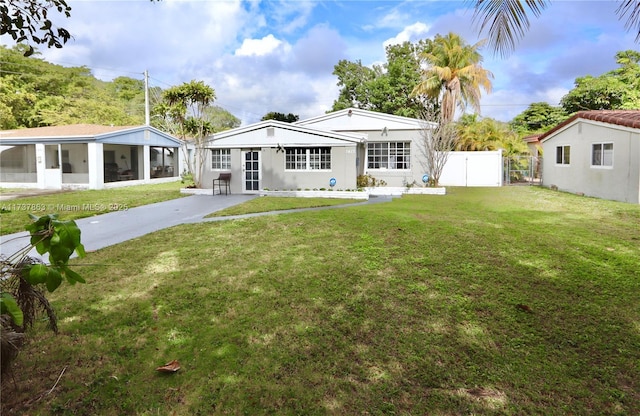 rear view of property with a gate, a lawn, fence, and a sunroom