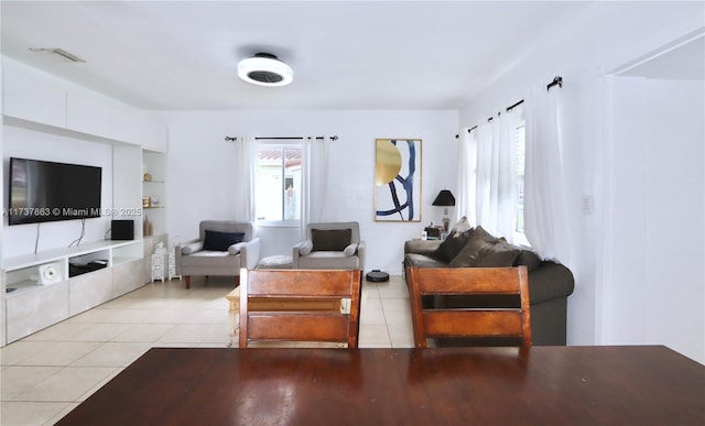 living area featuring light tile patterned floors, built in shelves, visible vents, and a wealth of natural light