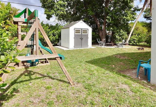 view of play area with a fire pit, a yard, a shed, and an outbuilding