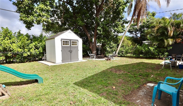 view of yard featuring a storage shed, an outdoor fire pit, a playground, and an outdoor structure