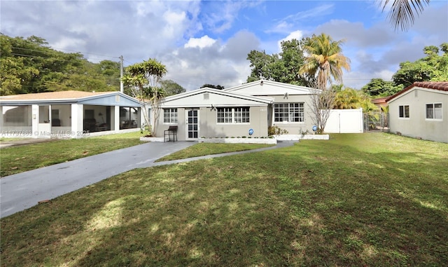 rear view of house featuring a sunroom, a gate, fence, and a lawn