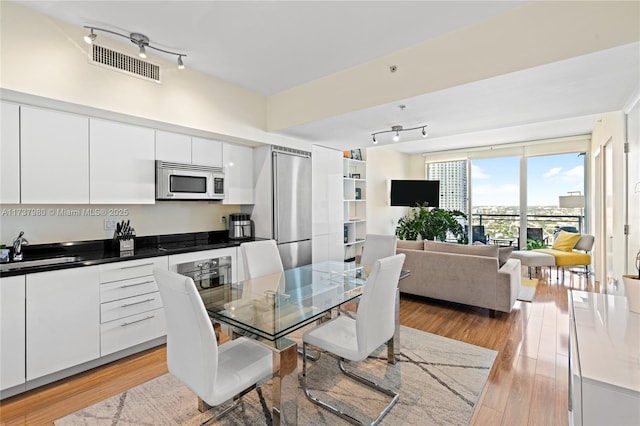 dining area with rail lighting, sink, and light hardwood / wood-style flooring