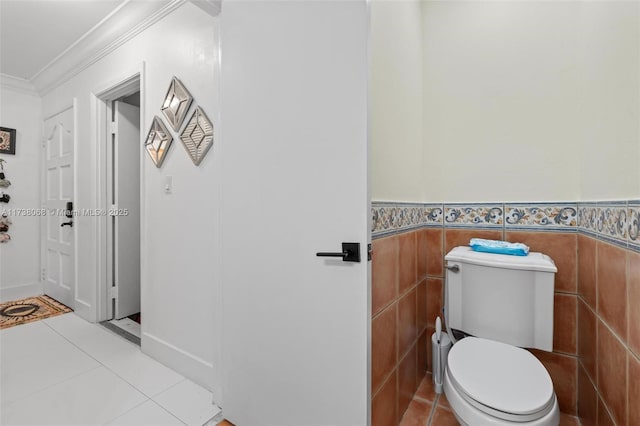 bathroom with ornamental molding, toilet, tile patterned flooring, and tile walls