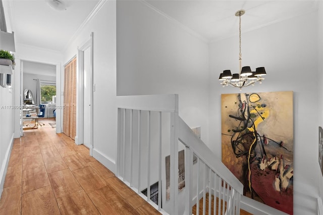 corridor with crown molding, an inviting chandelier, and light hardwood / wood-style flooring