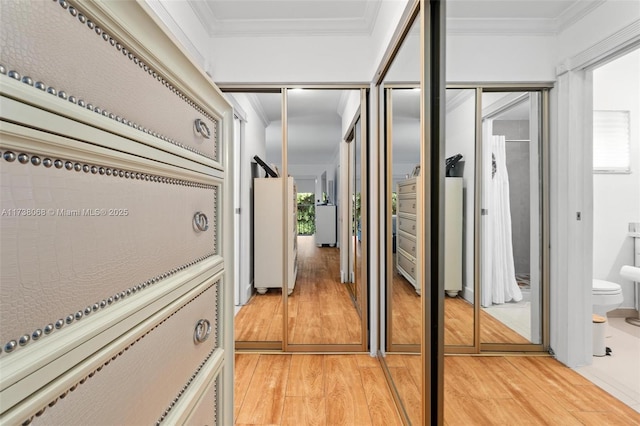 corridor with ornamental molding and light hardwood / wood-style floors