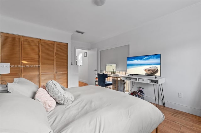 bedroom with crown molding, a closet, and light wood-type flooring