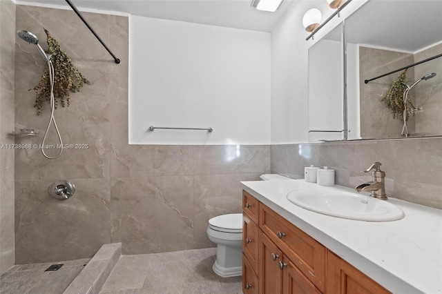 bathroom with vanity, a tile shower, tile walls, and toilet