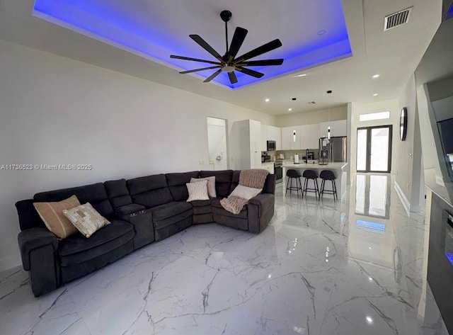 living room with ceiling fan and a tray ceiling