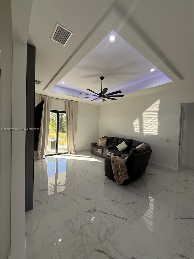 unfurnished living room featuring a tray ceiling and ceiling fan