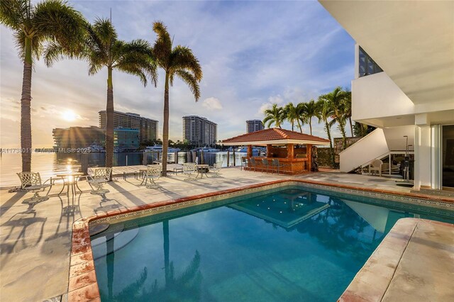 1740 S Bayshore Ln, Miami, FL 33133 - pool at dusk with a gazebo, a water view, a patio area, and a bar