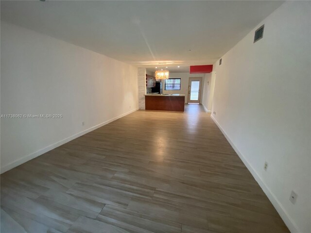 unfurnished living room featuring wood-type flooring and an inviting chandelier