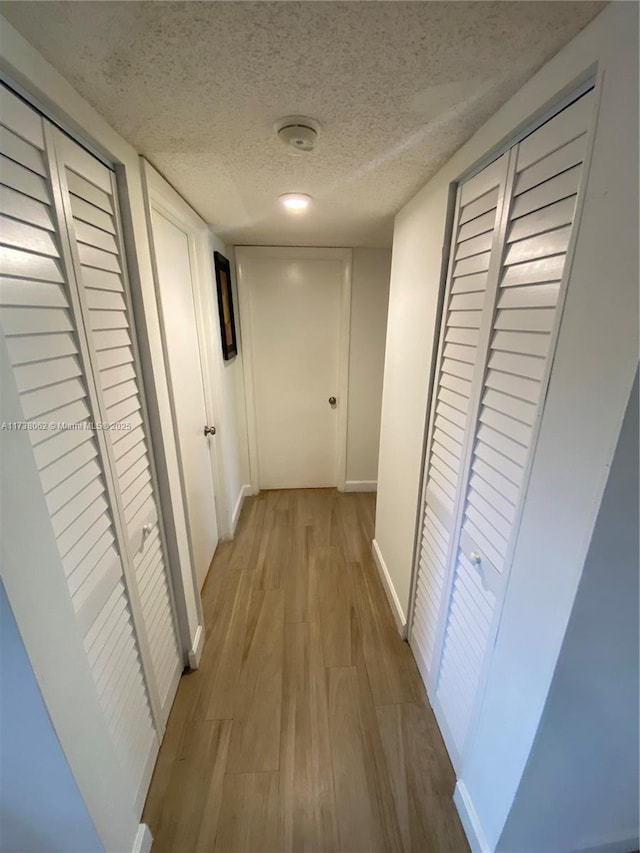 hallway featuring a textured ceiling and light wood-type flooring