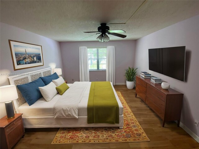 bedroom with ceiling fan, hardwood / wood-style floors, and a textured ceiling