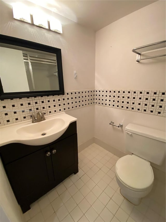 bathroom with tile patterned floors, vanity, toilet, and tile walls