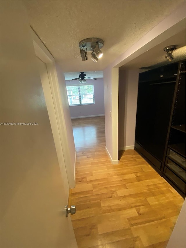 hall with light hardwood / wood-style floors and a textured ceiling