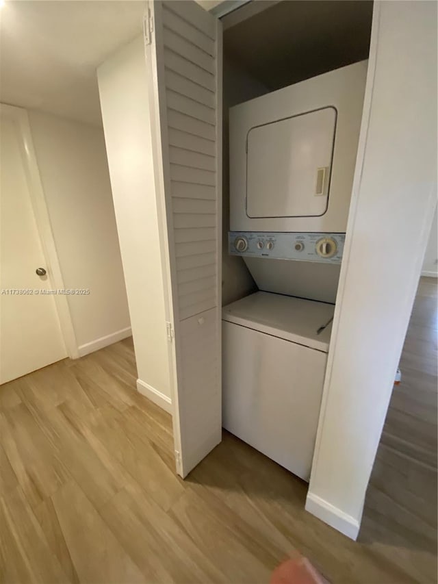 laundry area with stacked washer and dryer and light wood-type flooring