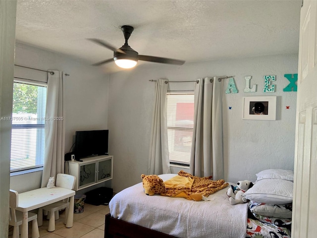 bedroom with ceiling fan, a textured ceiling, and light tile patterned floors