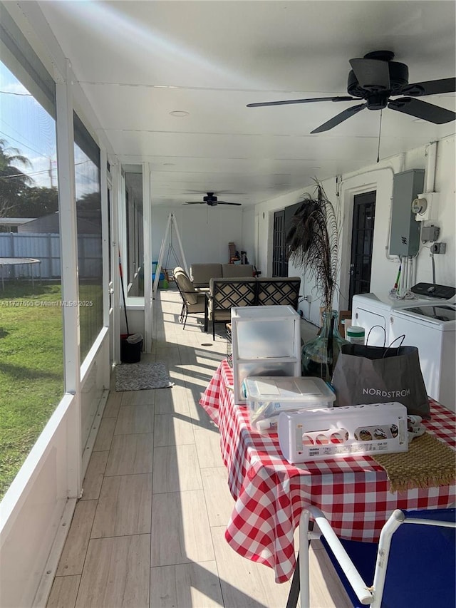 sunroom / solarium featuring washing machine and dryer, electric panel, and ceiling fan