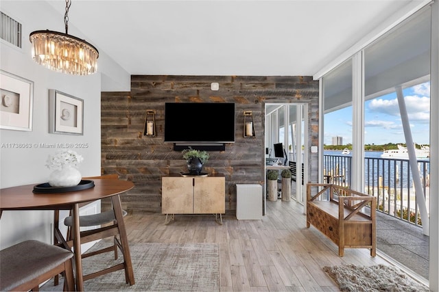 living room featuring hardwood / wood-style flooring, wooden walls, and a chandelier