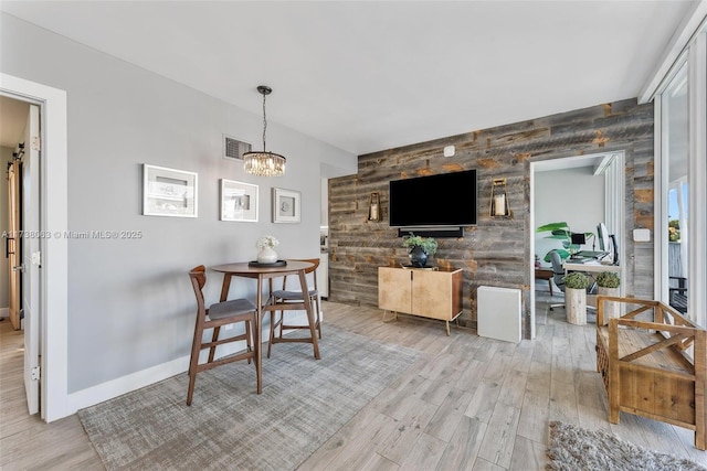 dining space featuring light wood-type flooring and a notable chandelier