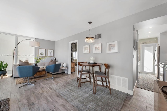 dining area with an inviting chandelier and light hardwood / wood-style flooring