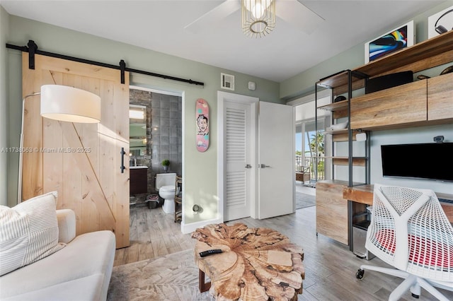 office space featuring light hardwood / wood-style floors, a barn door, and ceiling fan