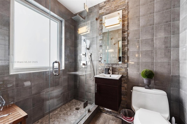 bathroom featuring vanity, toilet, an enclosed shower, and tile walls