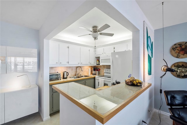 kitchen with ceiling fan, white appliances, a peninsula, a sink, and backsplash
