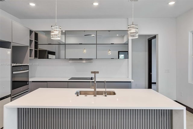 kitchen featuring stainless steel oven, gray cabinets, modern cabinets, and a sink