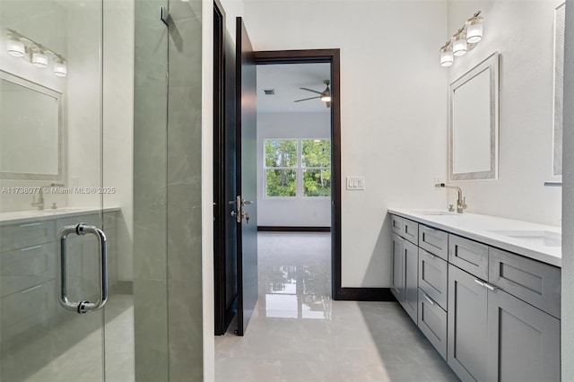 bathroom featuring double vanity, a stall shower, baseboards, and a sink