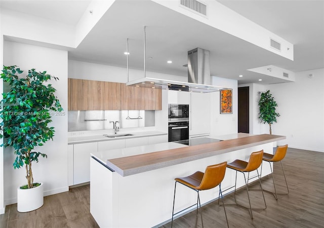 kitchen with black microwave, sink, a breakfast bar area, and white cabinets