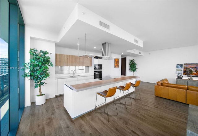 kitchen with dark hardwood / wood-style floors, white cabinetry, sink, and a kitchen bar