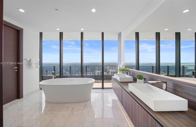 bathroom with vanity, a tub, expansive windows, and a water view