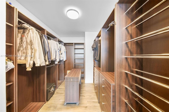 walk in closet with light hardwood / wood-style flooring