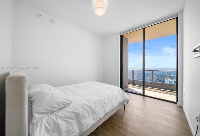 bedroom with a wall of windows, hardwood / wood-style floors, and access to outside