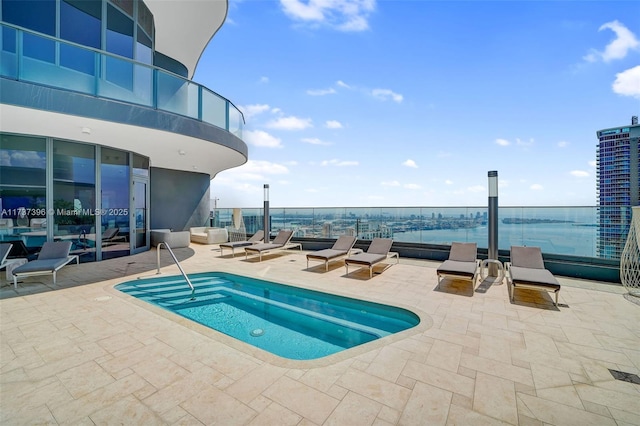 view of pool featuring a water view, an in ground hot tub, and a patio