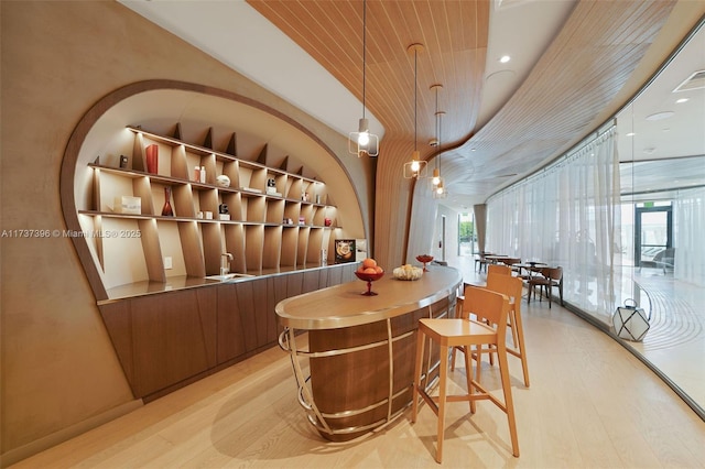 wine room with wood ceiling, built in features, a wall of windows, and light hardwood / wood-style floors