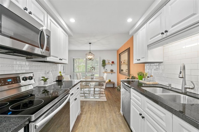 kitchen featuring white cabinetry, sink, decorative light fixtures, and appliances with stainless steel finishes