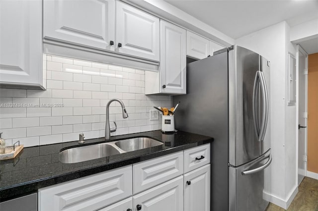 kitchen with sink, backsplash, stainless steel refrigerator, and white cabinets